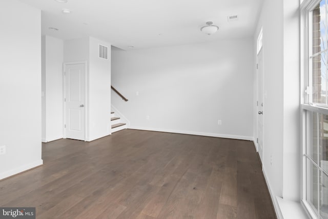 empty room featuring a wealth of natural light and dark hardwood / wood-style flooring