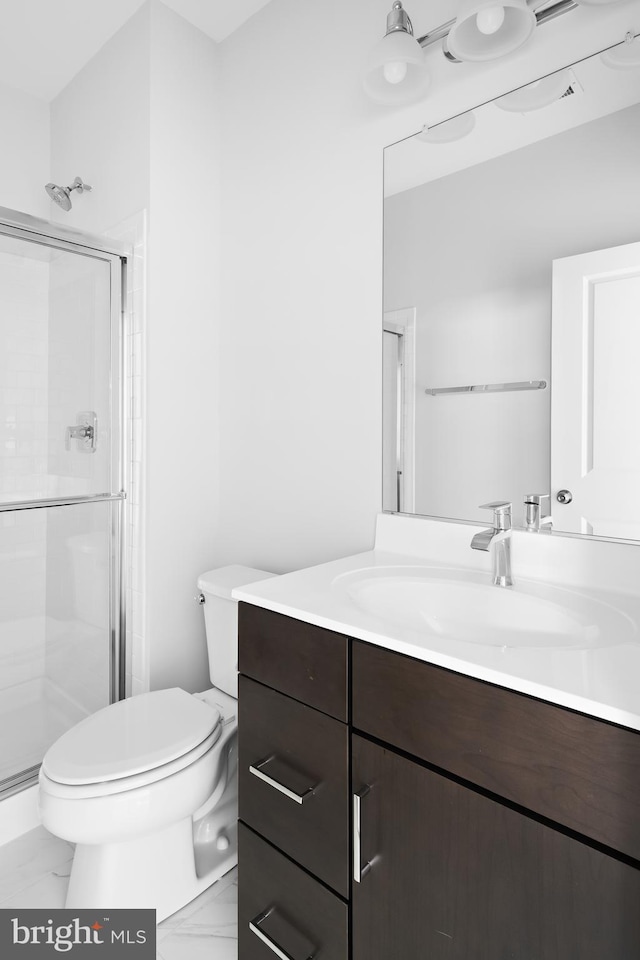 bathroom featuring vanity, toilet, and a shower with door