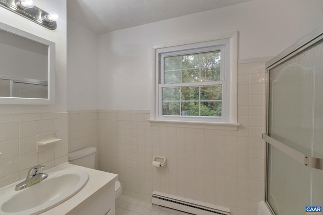 bathroom with a shower with shower door, toilet, tile walls, baseboard heating, and vanity