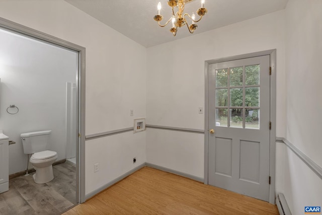 doorway to outside with light hardwood / wood-style flooring, a baseboard heating unit, and a notable chandelier