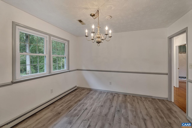 empty room with baseboard heating, light hardwood / wood-style flooring, a notable chandelier, and a textured ceiling