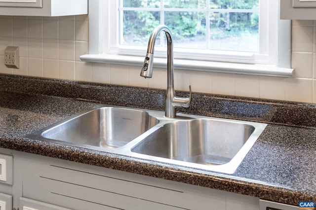 details with white cabinetry, sink, and backsplash