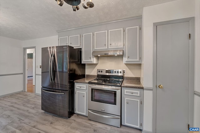 kitchen featuring stainless steel appliances, light wood-type flooring, white cabinets, a textured ceiling, and tasteful backsplash