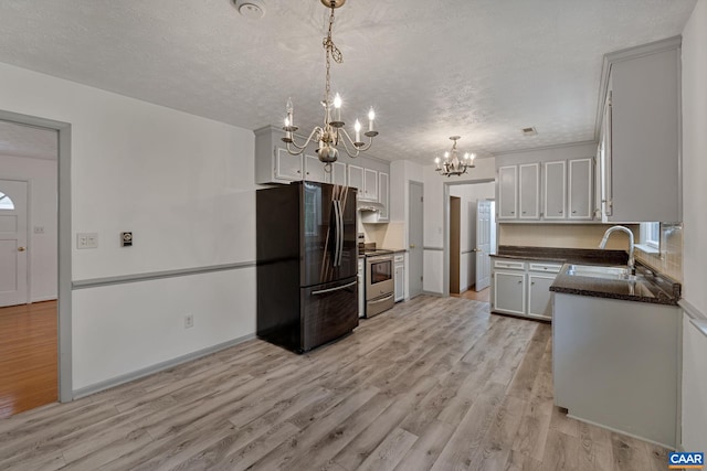 kitchen with black refrigerator, sink, light wood-type flooring, a textured ceiling, and electric stove