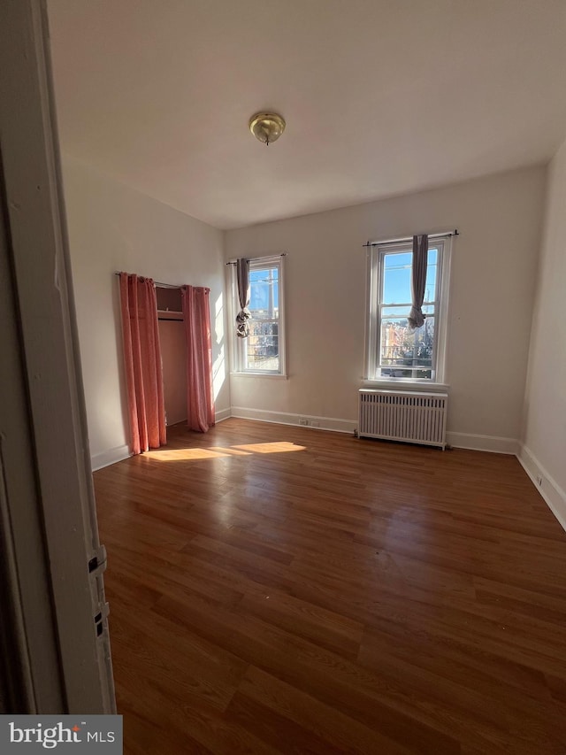 spare room featuring radiator heating unit and dark wood-type flooring