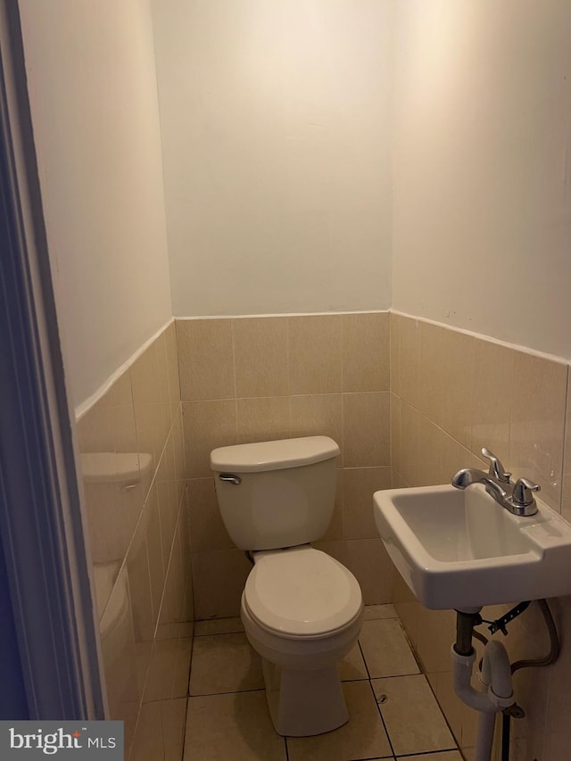 bathroom with tile walls, tile patterned floors, sink, and toilet