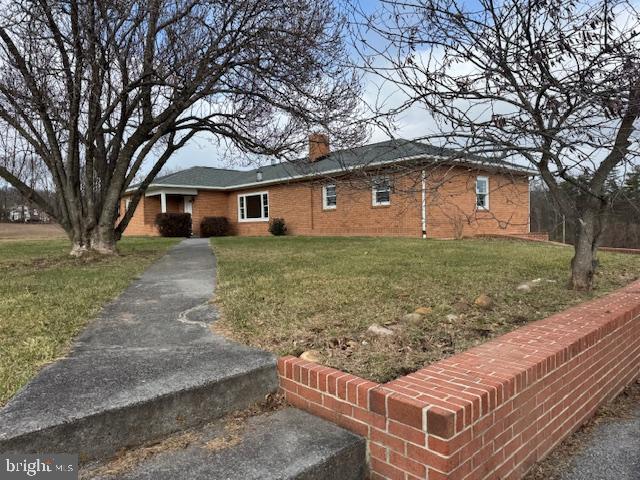 view of front of house featuring a chimney, a front lawn, and brick siding