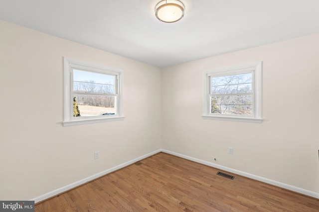 unfurnished room featuring a wealth of natural light and hardwood / wood-style floors