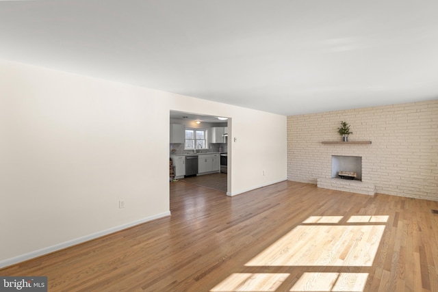 unfurnished living room with hardwood / wood-style flooring, sink, and a fireplace