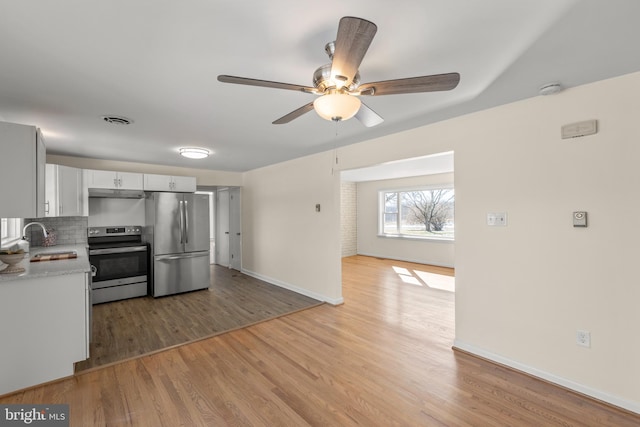 kitchen featuring sink, tasteful backsplash, light wood-type flooring, stainless steel appliances, and white cabinets