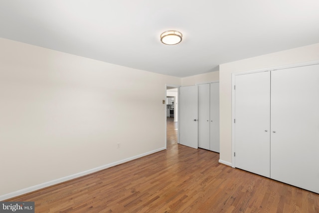 unfurnished bedroom featuring two closets and light wood-type flooring