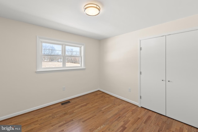 unfurnished bedroom with light wood-type flooring and a closet