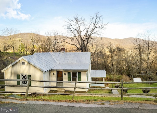view of front facade featuring metal roof, a chimney, a fenced front yard, and a mountain view