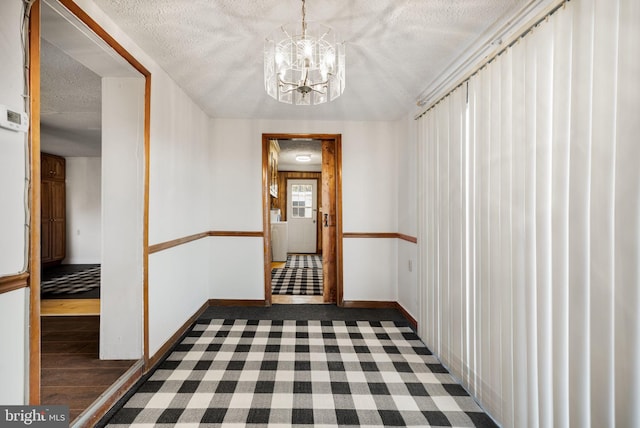 hallway featuring a textured ceiling, an inviting chandelier, and dark hardwood / wood-style flooring