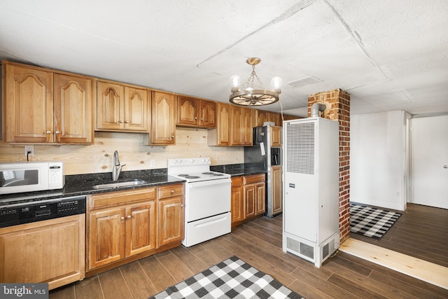 kitchen featuring white appliances, sink, dark wood-type flooring, decorative backsplash, and an inviting chandelier