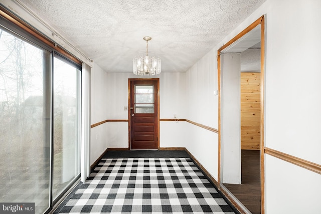 interior space with wood finished floors, baseboards, an inviting chandelier, and a textured ceiling