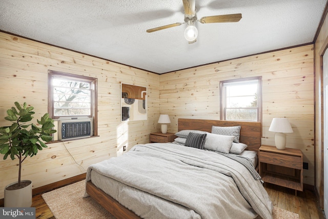bedroom featuring wooden walls, a textured ceiling, and multiple windows