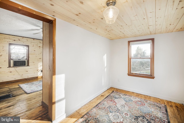 spare room with wood ceiling, hardwood / wood-style flooring, wooden walls, and ceiling fan