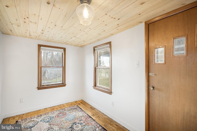 spare room featuring baseboards, a healthy amount of sunlight, wood ceiling, and light wood-type flooring