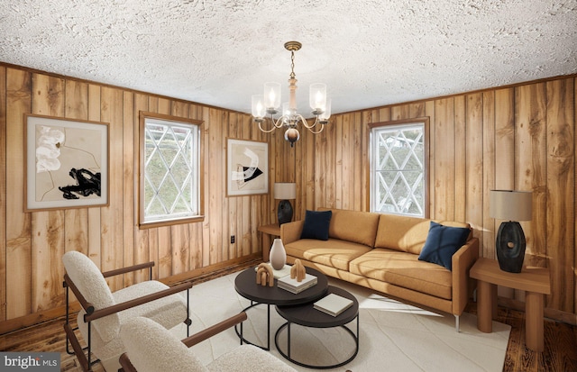 living room featuring a textured ceiling, an inviting chandelier, and wood walls