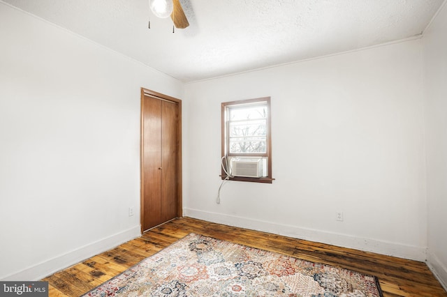 spare room featuring cooling unit, a textured ceiling, wood-type flooring, and ceiling fan