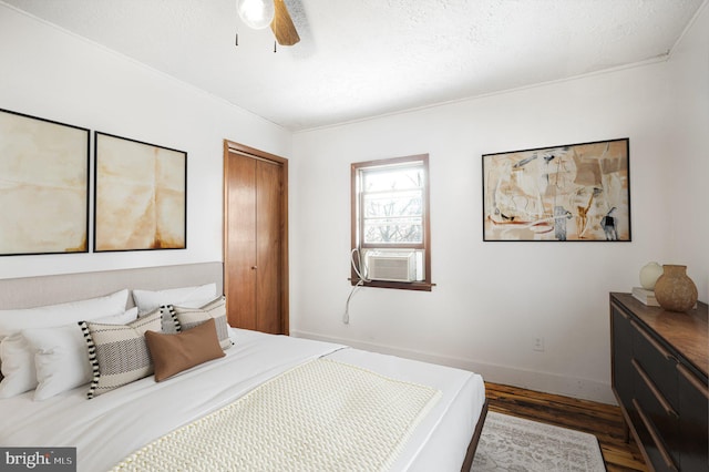 bedroom featuring wood finished floors, a closet, baseboards, cooling unit, and ceiling fan