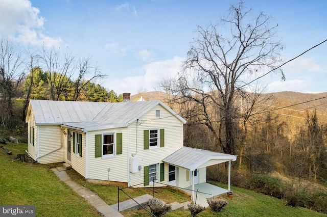 view of front of house featuring a chimney, a front lawn, and a carport
