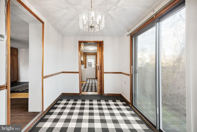 hallway featuring dark hardwood / wood-style floors, a textured ceiling, and an inviting chandelier