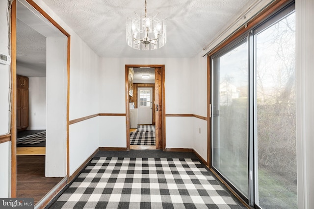 hall featuring baseboards, an inviting chandelier, and a textured ceiling