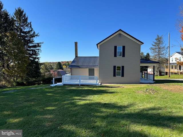 back of property featuring a lawn and a deck