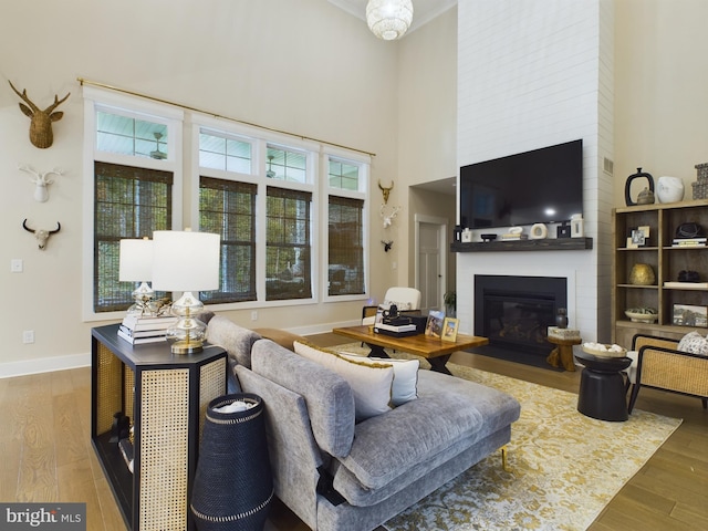 living room with a large fireplace, hardwood / wood-style flooring, and a towering ceiling