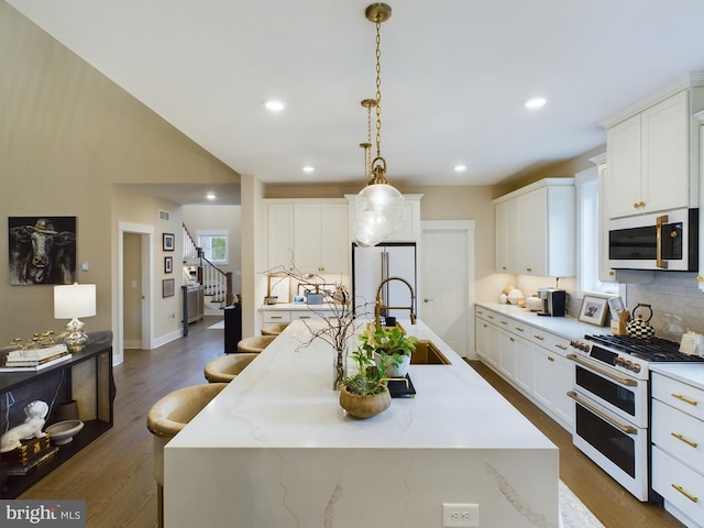 kitchen featuring an island with sink, white cabinetry, and white appliances