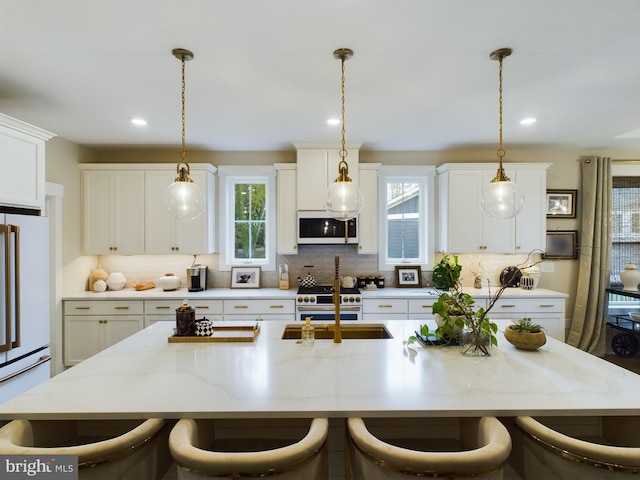 kitchen with white appliances, backsplash, decorative light fixtures, a breakfast bar area, and a kitchen island with sink