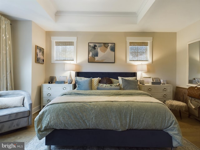 bedroom featuring ornamental molding, wood-type flooring, and a tray ceiling