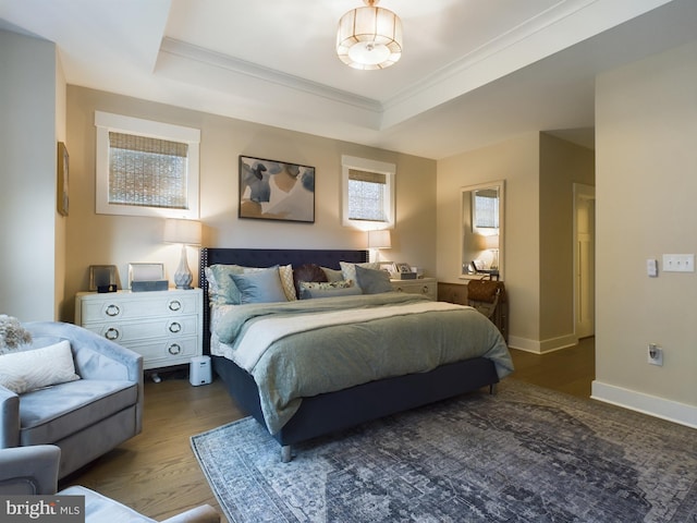 bedroom featuring a raised ceiling, wood-type flooring, and ornamental molding