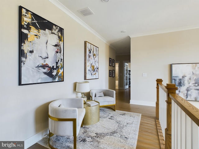 sitting room with ornamental molding and light hardwood / wood-style floors