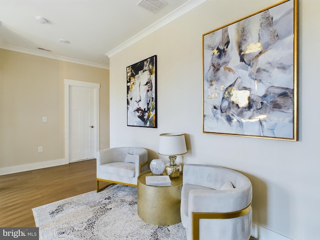 sitting room with ornamental molding and wood-type flooring