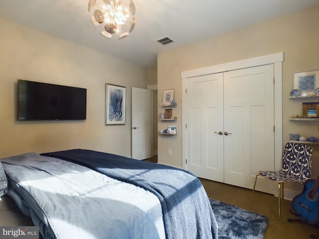 bedroom with dark wood-type flooring, a closet, and an inviting chandelier