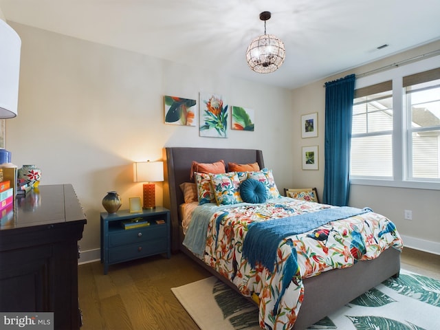 bedroom featuring dark wood-type flooring and an inviting chandelier