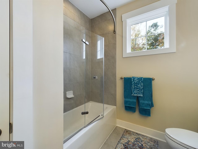 bathroom featuring toilet, bath / shower combo with glass door, and tile patterned flooring