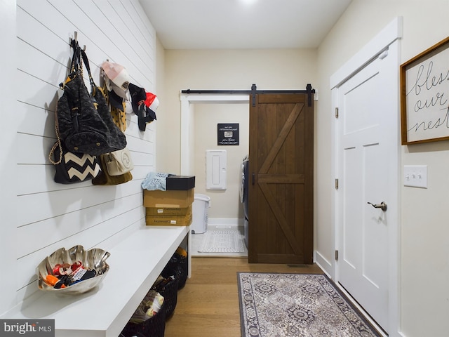 mudroom featuring wood walls, a barn door, light hardwood / wood-style floors, and washer / clothes dryer