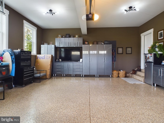 garage featuring a garage door opener and stainless steel fridge