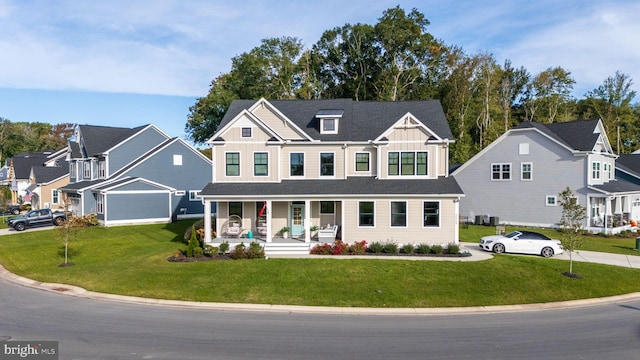 view of front of house featuring covered porch, a front yard, and a garage