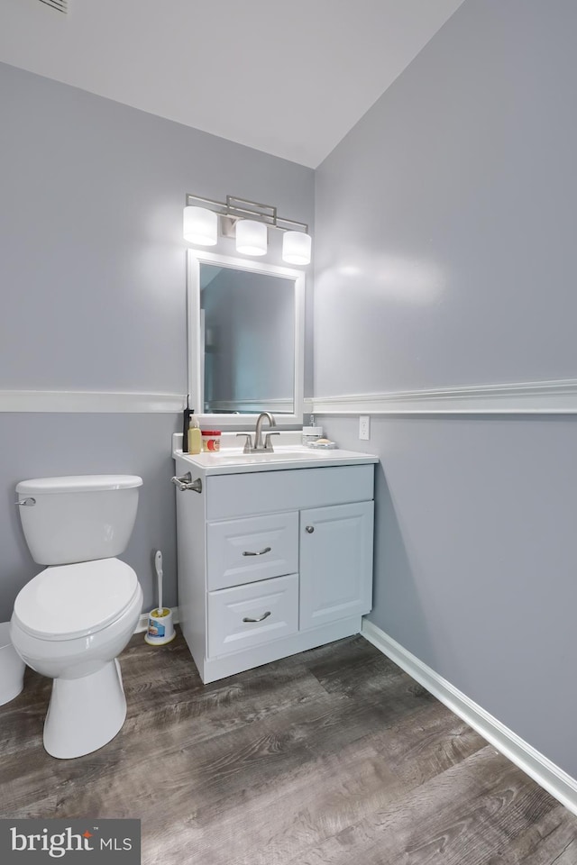 bathroom with hardwood / wood-style flooring, vanity, toilet, and vaulted ceiling