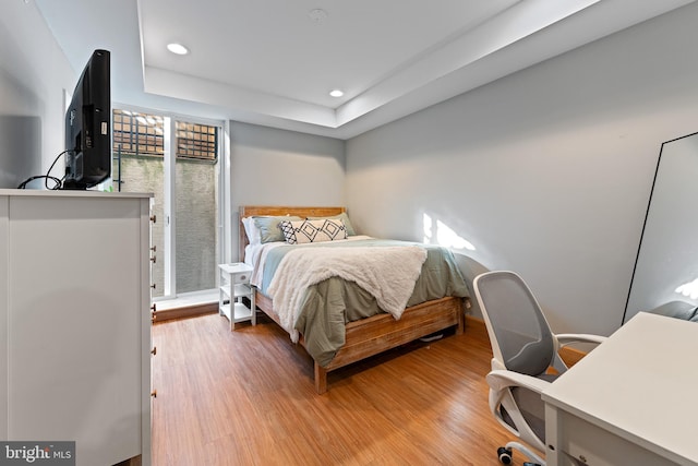 bedroom with hardwood / wood-style flooring and a tray ceiling