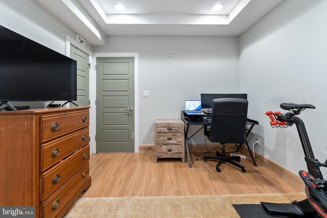 office space with a raised ceiling and light wood-type flooring