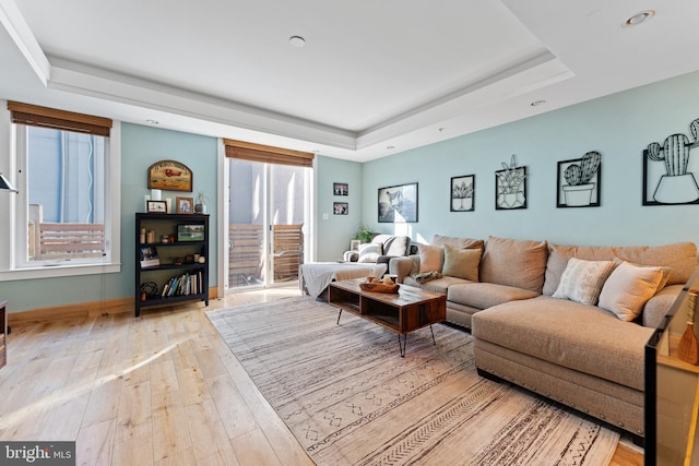 living room with a tray ceiling and light hardwood / wood-style floors