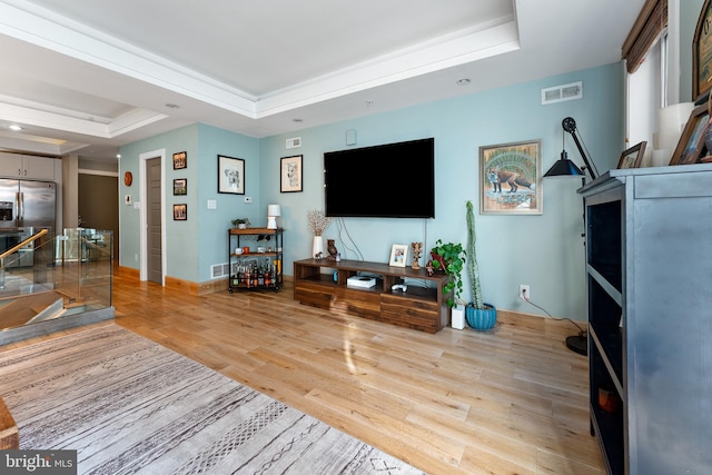 living room featuring light hardwood / wood-style flooring and a tray ceiling