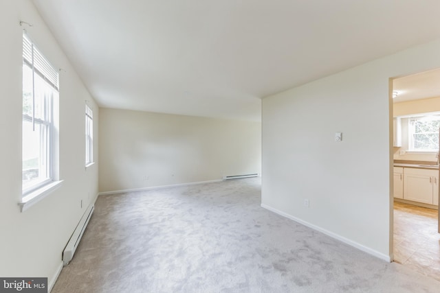 empty room with a baseboard heating unit and light colored carpet