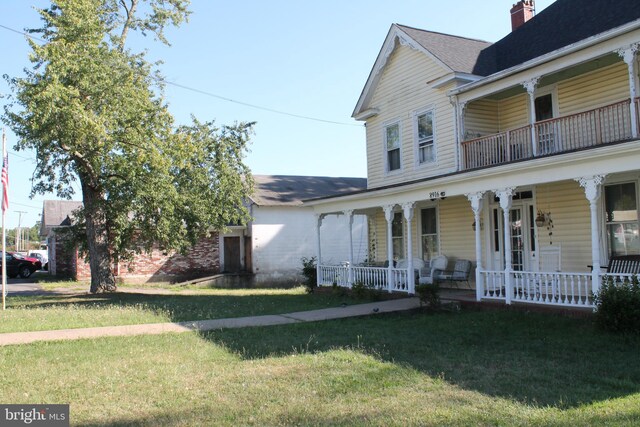 view of front of home featuring a balcony, a front lawn, and a porch